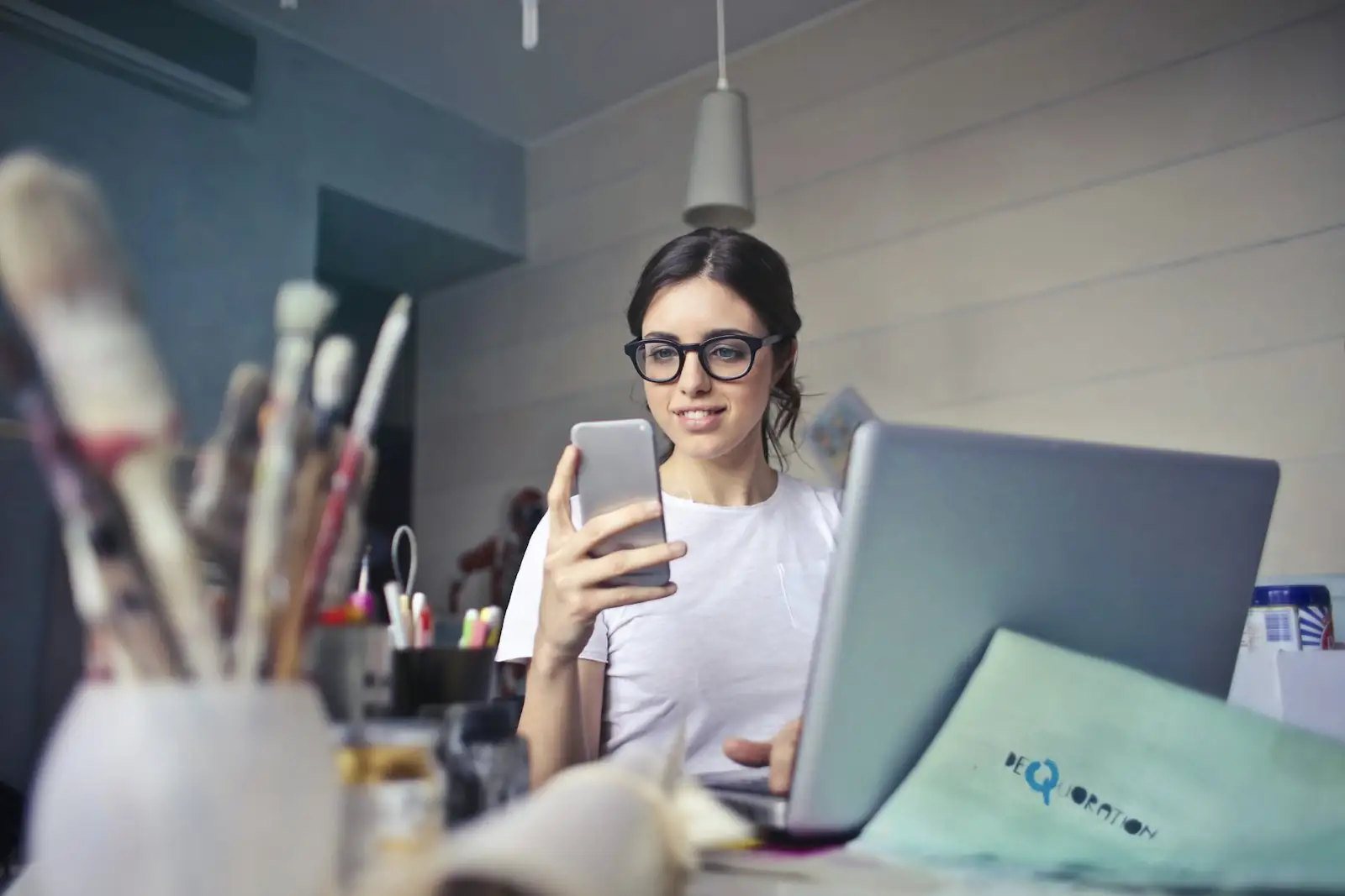 Business owner checking her phone at her laptop